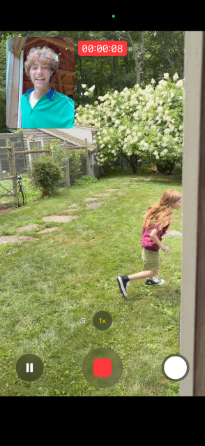 Tela do iPhone 17 mostrando a captura dupla das câmeras frontal e traseira com uma menina correndo enquanto um homem observa